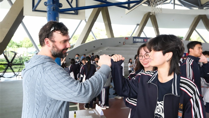 大明學子愉快與外國朋友交談，把英語學習化為日常互動，展現自信與國際視野。